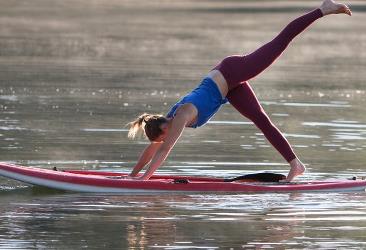 Kvinder laver yoga på SUP i vandet